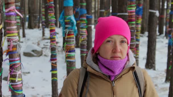 Portret dziewczyny w lesie zimą wśród drzew z kolorowymi wstążkami — Wideo stockowe