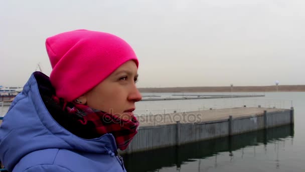 Portret van een lachende meisje op de pier op een koude, bewolkte dag in de herfst — Stockvideo