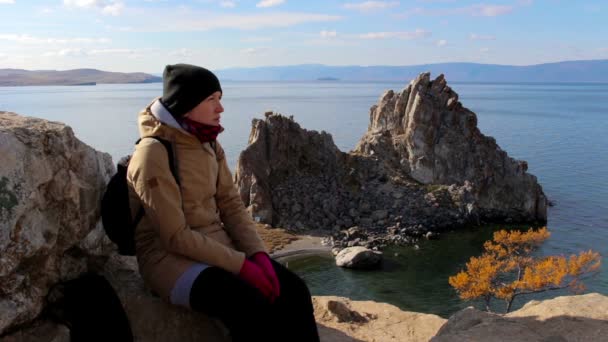 Mädchen sitzt auf einem Felsen am Meer auf einem Hintergrund von erstaunlicher Landschaft. — Stockvideo