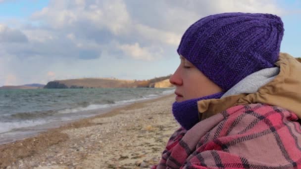 La chica se sienta en la orilla del mar y medita. Olas, hermoso paisaje — Vídeos de Stock