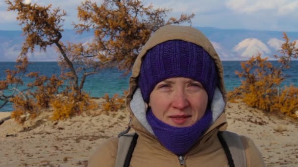 Portrait d'une fille vêtue d'une veste avec une capuche debout sur le rivage de la mer — Video