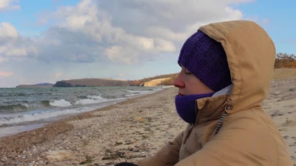 소녀는 바다의 해 안에 앉아서 묵상. 파도, 아름 다운 풍경 — 비디오