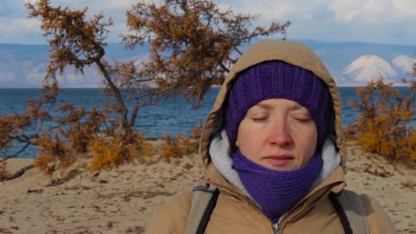 Retrato de uma menina em um casaco com um capuz meditando na costa do mar — Vídeo de Stock