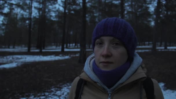 Menina olha em volta na floresta fria de inverno escuro — Vídeo de Stock