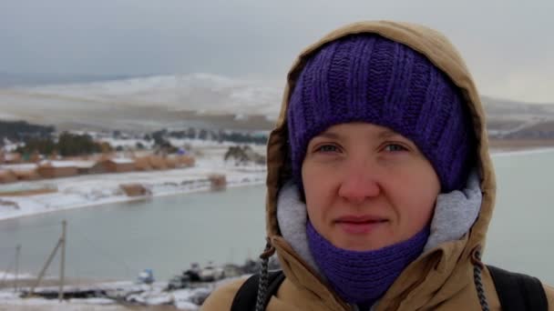 Портрет улыбающейся девушки в куртке с капюшоном у моря — стоковое видео