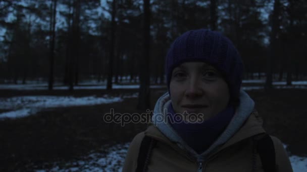 Egy hideg, sötét téli erdőben egy mosolygó lány portréja — Stock videók
