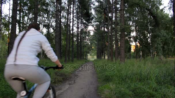 Девушка в спортивной одежде с косой на велосипеде в парке . — стоковое видео