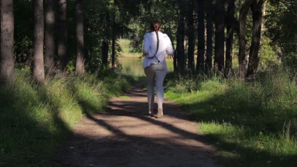 Kız bir gölgeli orman yeşil sokak çalışır. Genç kadın parkta koşu — Stok video