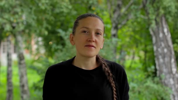 Retrato de una niña sobre un fondo de follaje verde de abedules en el verano — Vídeos de Stock