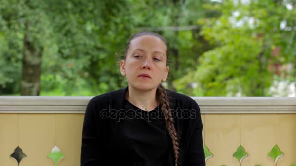 Retrato de una chica pensativa con trenza vestida de negro sentada en el cenador — Vídeos de Stock