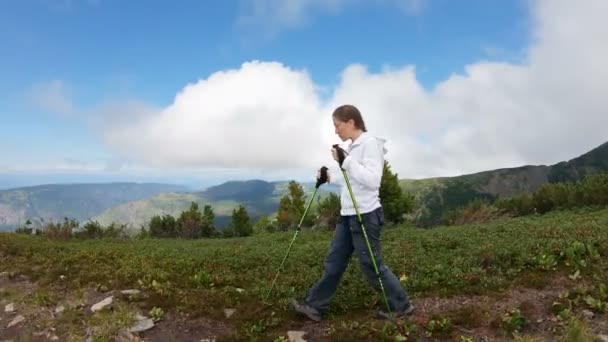 Caminhe nas montanhas. Menina com postes de trekking vai alto nas montanhas — Vídeo de Stock