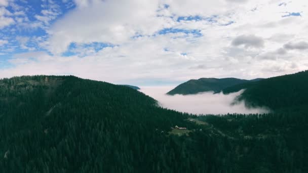 Панорама горного пейзажа. Долина заполнена туманом, лесистыми горами, домами — стоковое видео