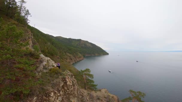 Το κορίτσι σκαρφαλώνει στον γκρεμό σε μια βραχώδη ακτή. Αεροφωτογραφία — Αρχείο Βίντεο