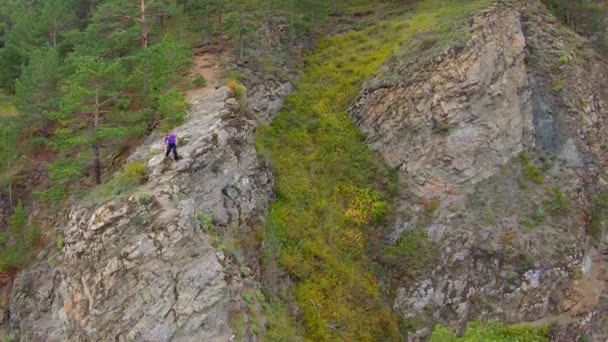 Śledzenie z powietrza dziewczyny schodzącej na skałę — Wideo stockowe