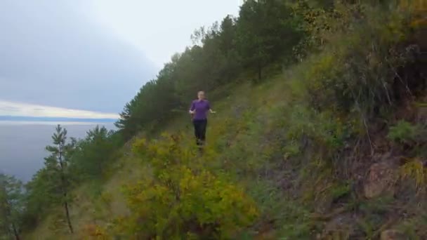 Meisje loopt langs het pad van een steile helling aan de kust — Stockvideo