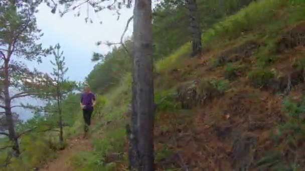 Chica corre a lo largo del camino de una pendiente empinada en la costa — Vídeo de stock