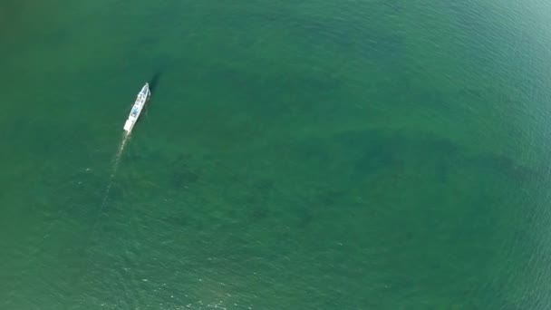 Vista aérea de la superficie del agua arriba hacia abajo. Un barco blanco navega en agua verde — Vídeo de stock