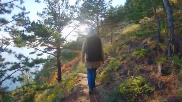 Жінка-турист з рюкзаком, що йде на узбережжі в сонячний день — стокове відео