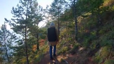 Sırt çantalı kadın turist güneşli bir günde deniz kıyısında yürüyor.