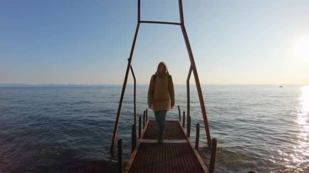 En flicka går längs piren på stranden — Stockvideo