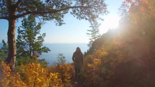 Girl climbs up a path on steep slope of Baikal shore on bright sunny autumn day — Stock Video