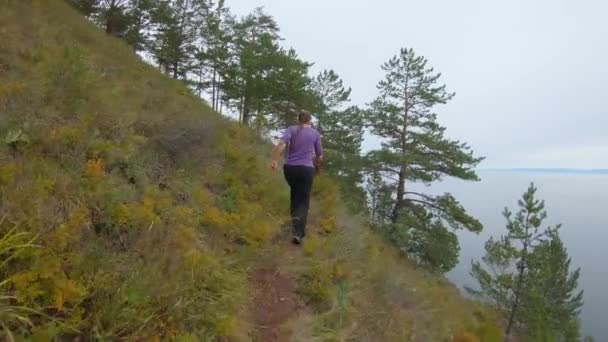 Kobieta biegająca wzdłuż ścieżki w górach. Widok z tyłu — Wideo stockowe