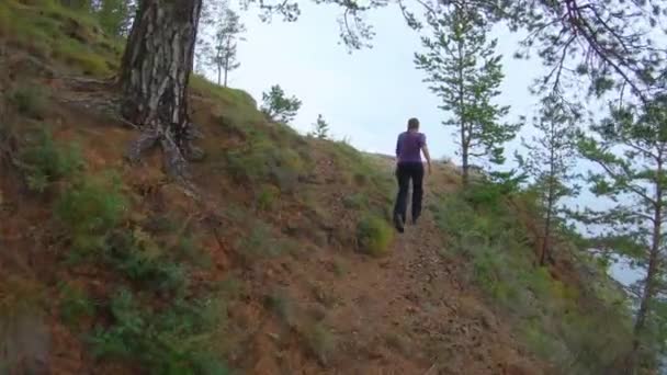 Девушка бежит вверх по горе с прекрасным видом и поднимает руки вверх — стоковое видео