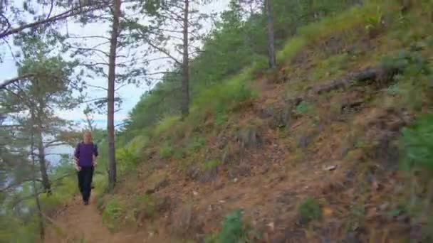 Dziewczyna z plecakiem biegnie ścieżką stromego zbocza — Wideo stockowe