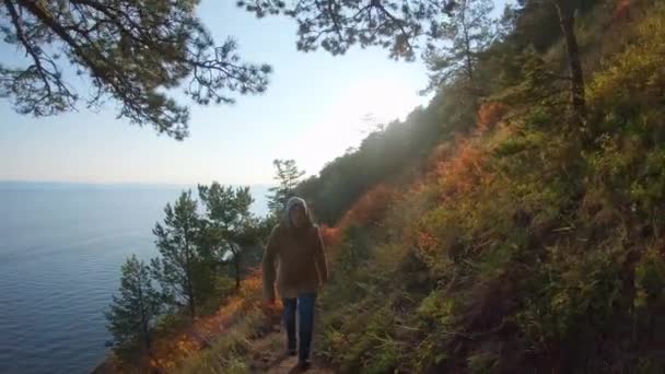 Mädchen erklimmt die steile Meeresküste. Die strahlende Herbstsonne scheint — Stockvideo