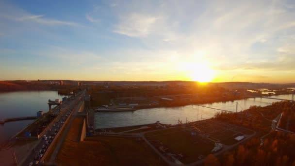 Drone vliegt over een dam waar auto 's bij zonsondergang rijden. Luchtfoto — Stockvideo