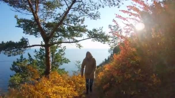 Dziewczyna wspina się po ścieżce na stromym zboczu morza w słoneczny jesienny dzień — Wideo stockowe