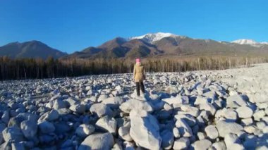 İHA, büyük kayalıklarda duran bir kızın üzerinden uçuyor.