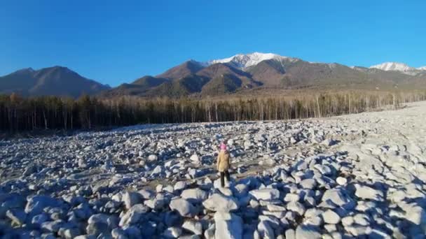 Dron przelatujący nad dziewczyną stojącą na polu wielkich kamieni — Wideo stockowe