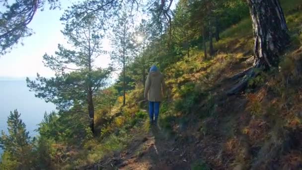 Una chica camina por la costa en un soleado día de otoño. Movimiento lento — Vídeo de stock