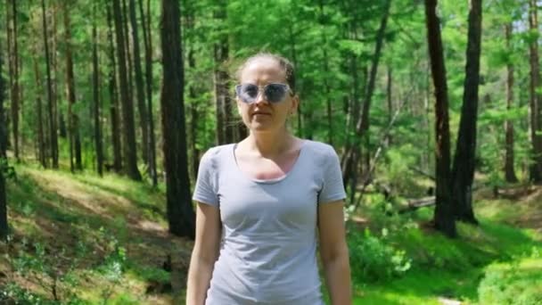 Una chica con gafas azules está en un bosque verde. Cámara lenta, 4K — Vídeos de Stock