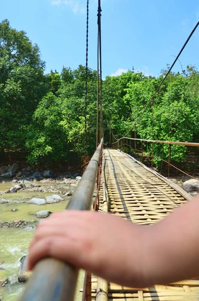 Ahşap bir asma köprü, demir demiryolu tutan el