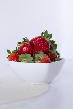 Beyaz zemin üzerinde bir seramik kase taze çilek. 