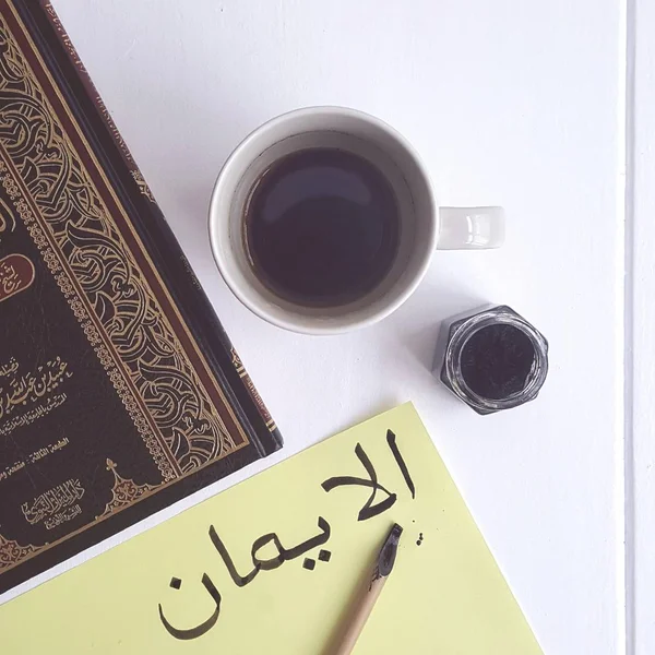 Caligrafía árabe Al Iman - Fe en la mesa con café y libro islámico. Foto: . — Foto de Stock