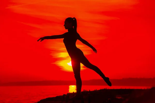 Silhouette de femme faisant de la méditation de yoga pendant le coucher du soleil avec la lumière naturelle du soleil doré sur la mer . — Photo