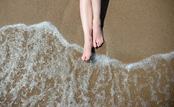 Feet on the sand on the background of the sea wave top view. Woman legs at beach on wooden swing. Relax and Single woman concept. Happiness and lifestyle concept.