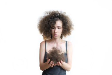 Kız kayıp saçlarını elinde tutuyor ve hayal kırıklığıyla onlara bakıyor. Rasta çıkardıktan sonra kabarık saçlar. Kız fırçasını uzun, zarar görmüş saçlarıyla gösteriyor ve saçlarına bakıyor. İzole edilmiş