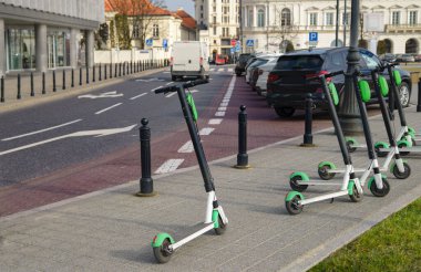 Elektrikli scooter yolda park etmiş. Modern ekolojik şehir mobiletleri kaldırım kenarında kiralık. Alternatif taşıma. E-scooterlar bir uygulama ile kiralanabilir