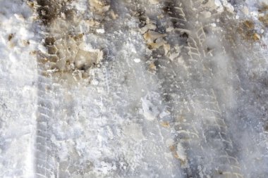 Winter road with tire tracks and human feet.