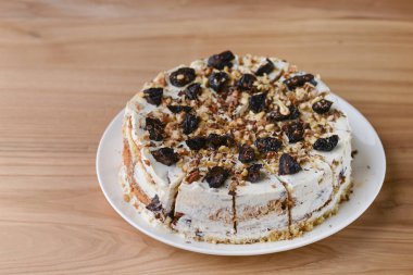 Beyaz bir tabakta servis edilen kuru erik, ceviz ve kremalı vanilyalı kek bisküvisi.