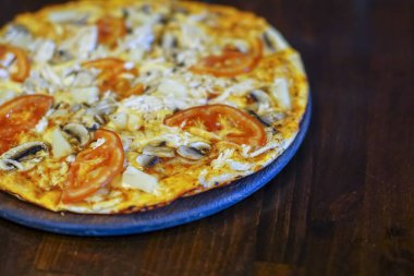 Tahtada servis edilen et, domates ve mantarlı leziz taze pizza.