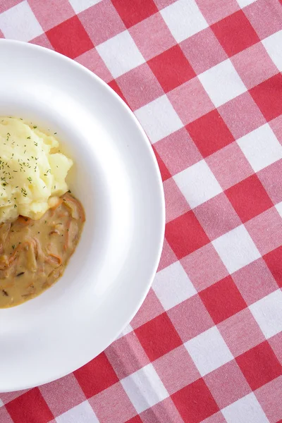 Cocina tradicional, puré de papas con salsa, carne y eneldo servido en un plato blanco sobre un fondo escocés —  Fotos de Stock