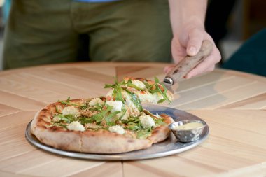 Lokantada hafif ahşap bir masada servis edilen lezzetli İtalyan büyük pizzası. Restoran yemek fotoğrafçılığı.