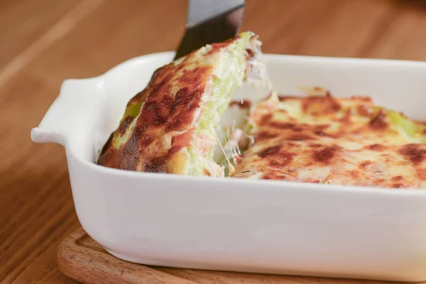 Classic lasagna with bolognese sauce, with cheese layered between sheets served in a white plate on a wooden background — Stock Photo, Image