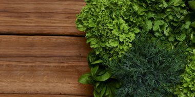 Açık ahşap zemin üzerinde taze yeşil marul salatası karışımı.