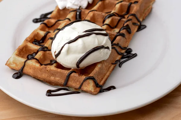 Plate of belgian waffles dessert with ice cream and chocolate caramel sauce on wooden table background. — Stock Photo, Image